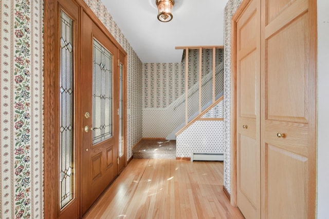 foyer entrance featuring baseboard heating and light hardwood / wood-style flooring