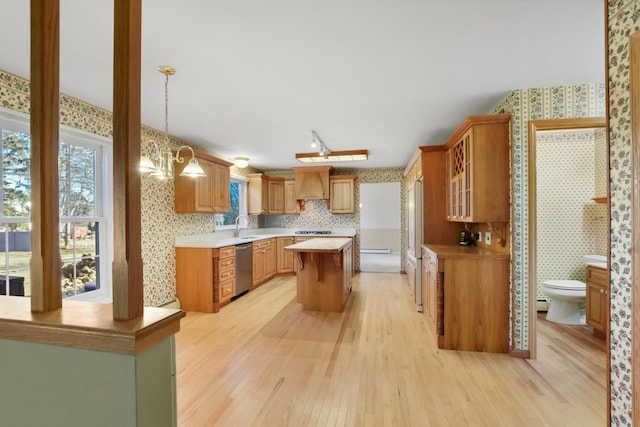 kitchen featuring dishwasher, a center island, sink, light hardwood / wood-style floors, and custom range hood