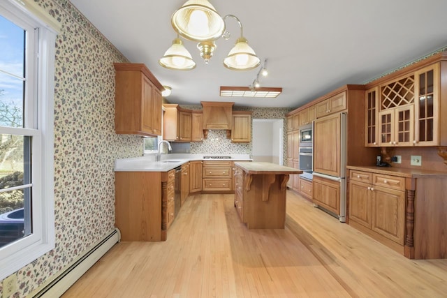 kitchen with a center island, a baseboard heating unit, sink, hanging light fixtures, and custom range hood