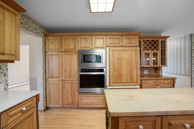 kitchen with tasteful backsplash, built in appliances, and light hardwood / wood-style flooring