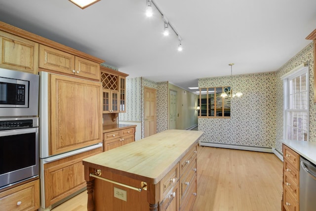 kitchen with a center island, stainless steel appliances, wood counters, a baseboard heating unit, and decorative light fixtures