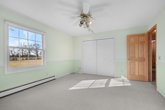 unfurnished bedroom with ceiling fan, a closet, light carpet, and a baseboard heating unit