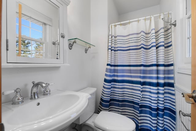 bathroom with walk in shower, sink, and toilet