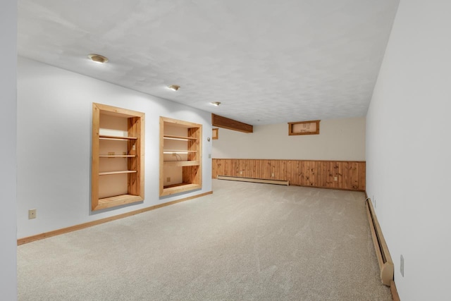 interior space featuring a textured ceiling, built in shelves, wood walls, and baseboard heating