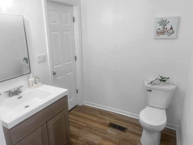 bathroom with hardwood / wood-style floors, vanity, and toilet