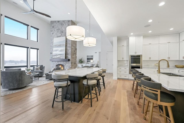 kitchen with pendant lighting, a kitchen bar, sink, decorative backsplash, and light stone counters