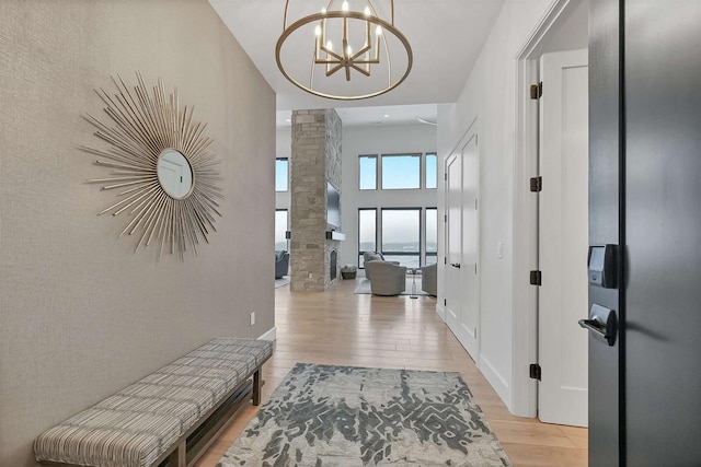 corridor featuring light hardwood / wood-style floors, decorative columns, a high ceiling, and an inviting chandelier