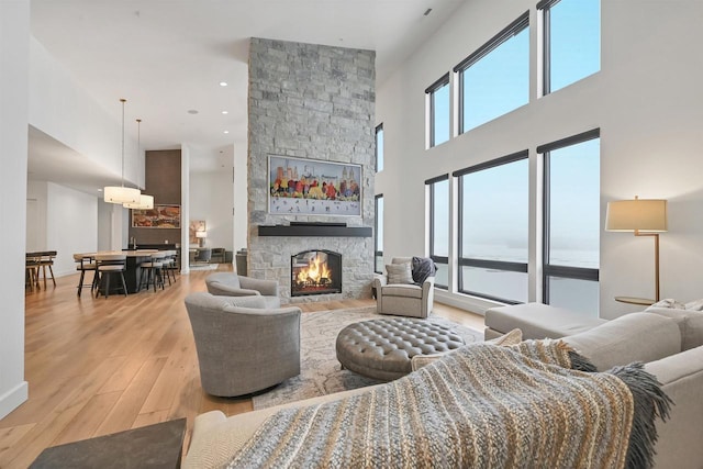 living room with a towering ceiling, a fireplace, and light hardwood / wood-style flooring