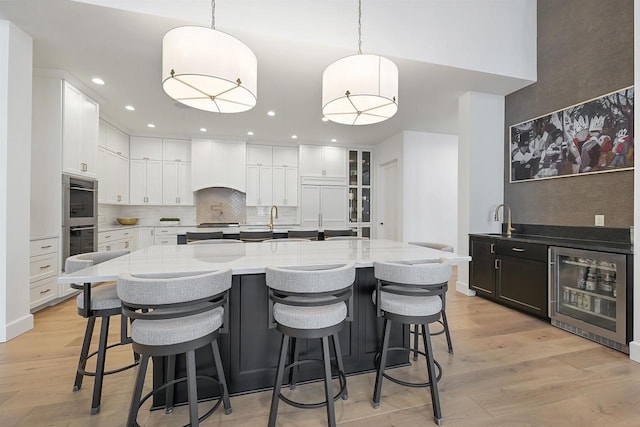 kitchen with a spacious island, premium range hood, hanging light fixtures, and beverage cooler