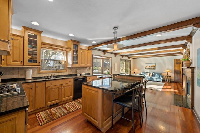 kitchen with black dishwasher, a center island, sink, pendant lighting, and beamed ceiling