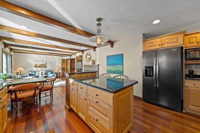 kitchen featuring black microwave, a kitchen island, stainless steel fridge, and beamed ceiling