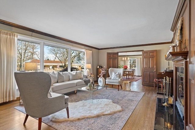 living room featuring a healthy amount of sunlight, a fireplace, ornamental molding, and hardwood / wood-style floors