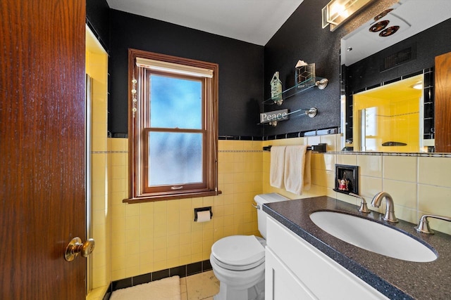 bathroom with toilet, vanity, tile patterned flooring, tile walls, and a shower with shower door