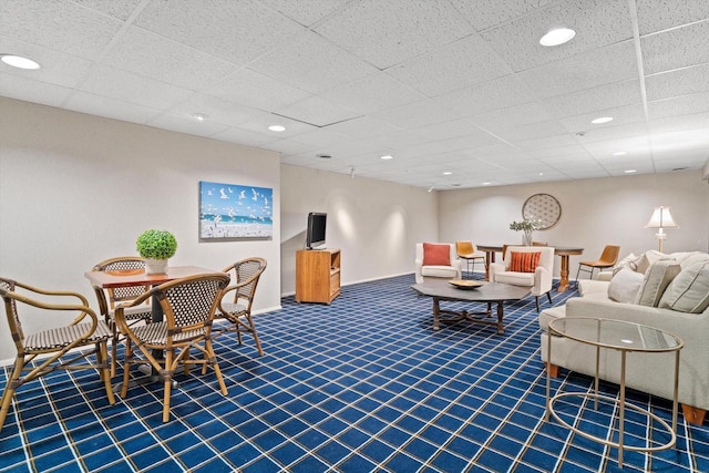 living room featuring a drop ceiling and carpet