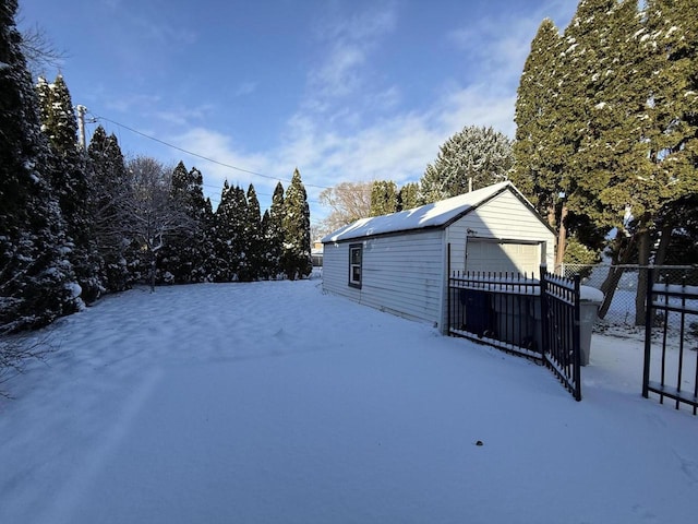 yard layered in snow with a garage and an outbuilding