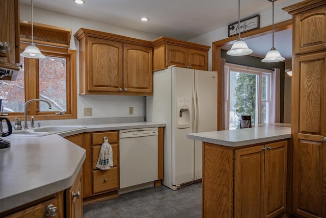 kitchen featuring sink, pendant lighting, and white appliances