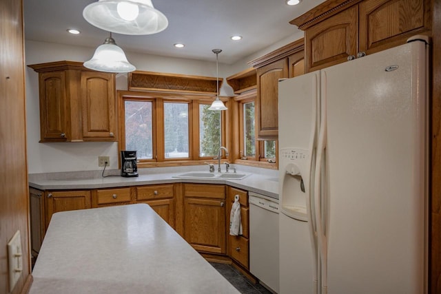 kitchen featuring white appliances, sink, and hanging light fixtures