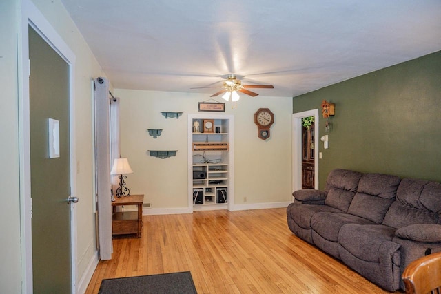 living room featuring built in features, ceiling fan, and light wood-type flooring