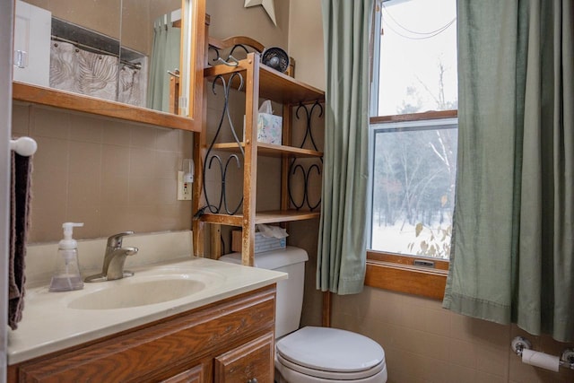 bathroom with vanity, plenty of natural light, tile walls, and toilet