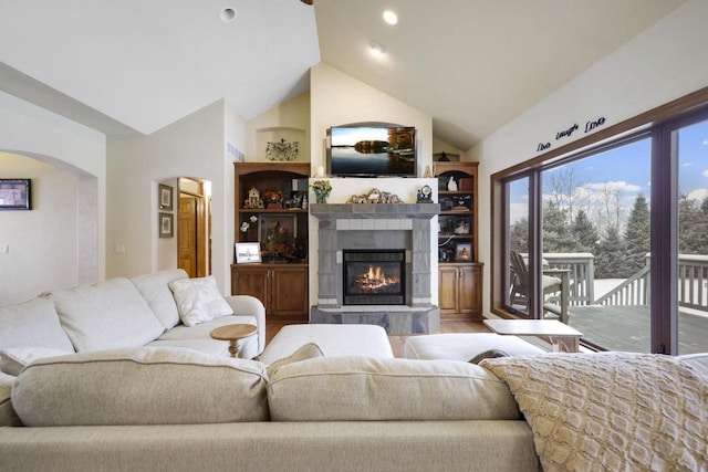 living room with a tile fireplace, hardwood / wood-style floors, and lofted ceiling