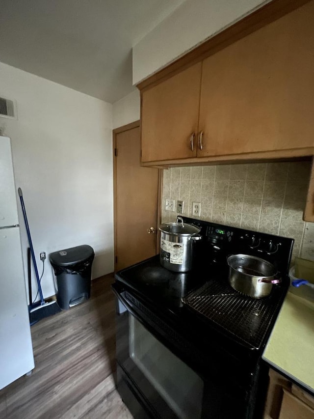 kitchen featuring wood-type flooring, electric range, white refrigerator, and tasteful backsplash