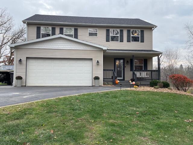 front facade featuring a porch, a garage, and a front lawn