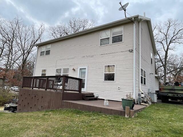 rear view of property featuring a lawn and a wooden deck