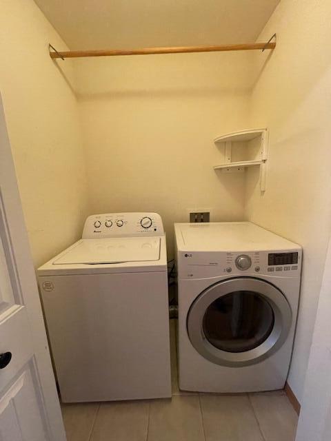 laundry area with washer and clothes dryer and light tile patterned floors