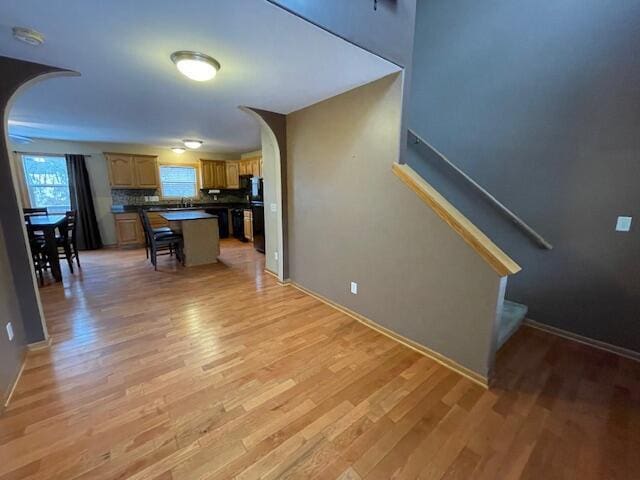 kitchen featuring a kitchen breakfast bar, a kitchen island, light hardwood / wood-style floors, and tasteful backsplash