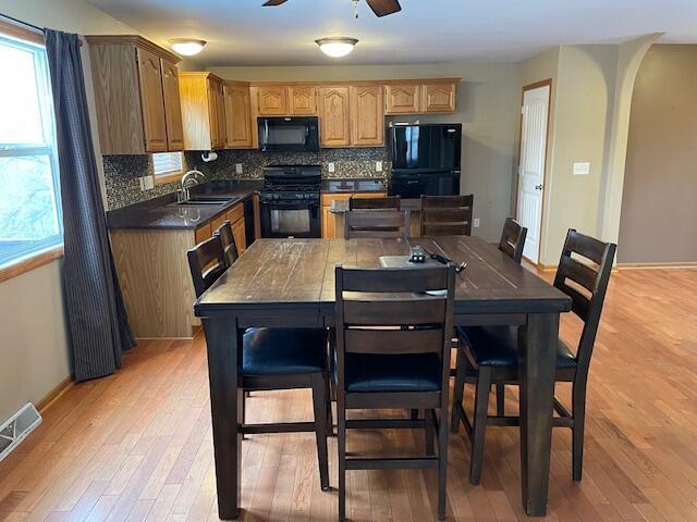 kitchen with ceiling fan, sink, tasteful backsplash, light hardwood / wood-style floors, and black appliances