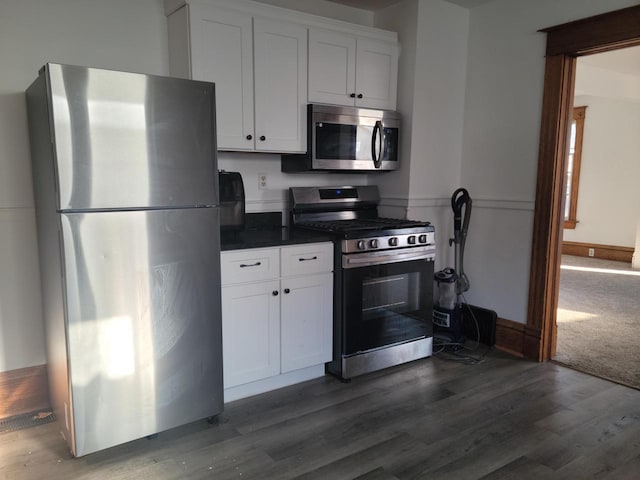 kitchen with appliances with stainless steel finishes, dark hardwood / wood-style floors, and white cabinetry