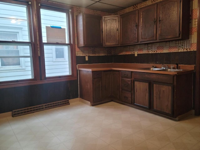 kitchen with dark brown cabinetry, sink, and a baseboard heating unit