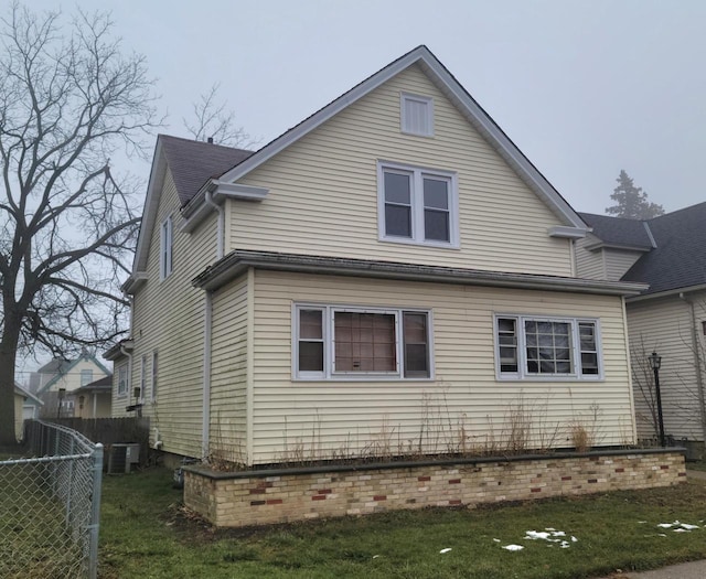 rear view of house featuring a lawn and central air condition unit