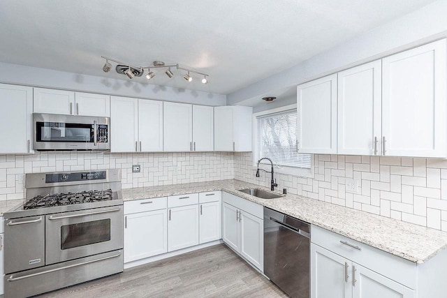 kitchen featuring sink, white cabinets, light hardwood / wood-style floors, and appliances with stainless steel finishes