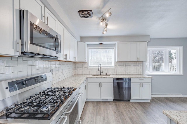 kitchen with sink, light stone countertops, appliances with stainless steel finishes, tasteful backsplash, and white cabinetry