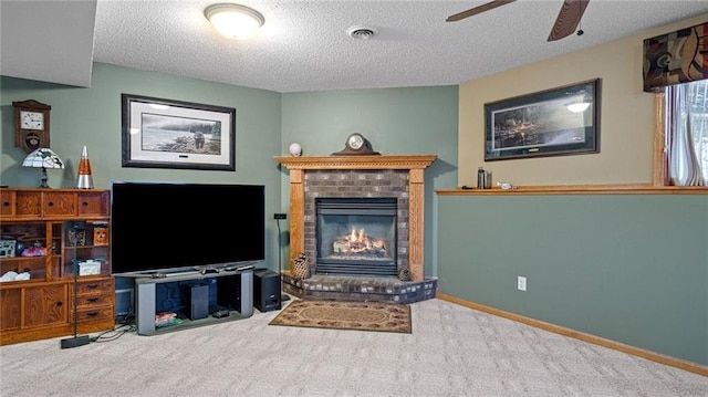 living room with carpet flooring, ceiling fan, a textured ceiling, and a brick fireplace