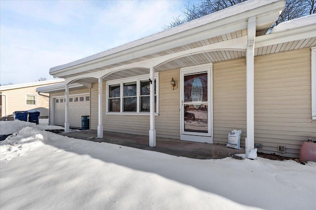 snow covered property entrance featuring a garage