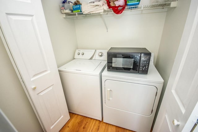 laundry area with washing machine and dryer and light hardwood / wood-style floors