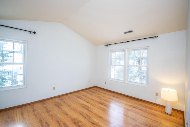 unfurnished room with plenty of natural light, light hardwood / wood-style floors, and lofted ceiling