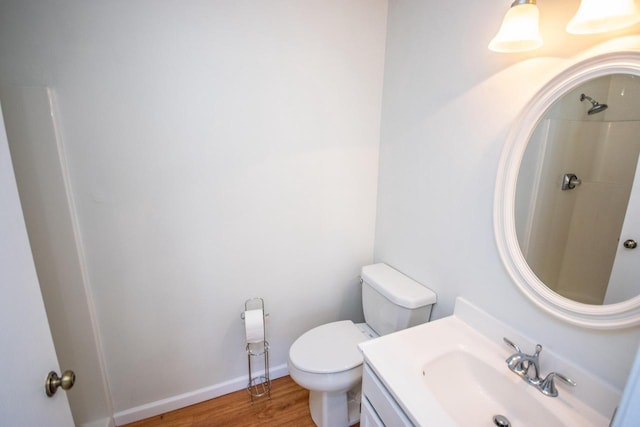 bathroom featuring hardwood / wood-style flooring, toilet, vanity, and walk in shower