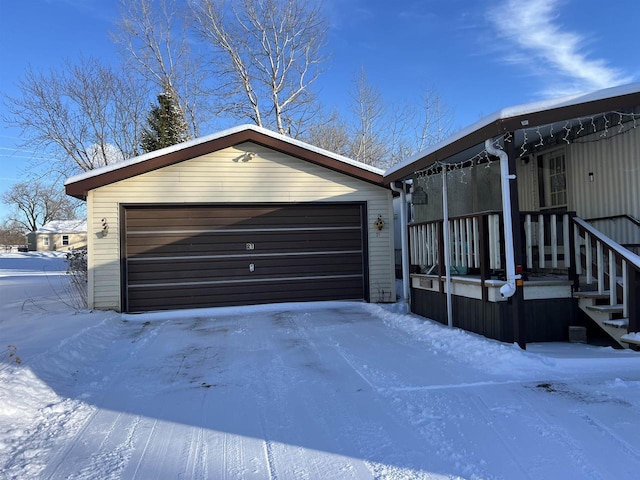 snow covered property featuring an outbuilding and a garage