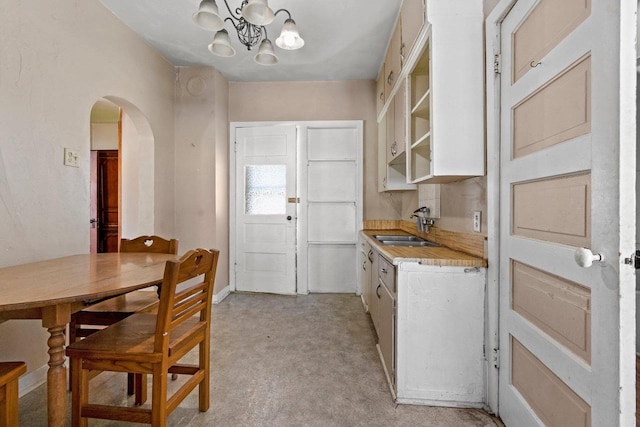 kitchen with a chandelier, white cabinets, and sink