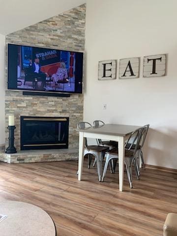 dining room featuring hardwood / wood-style flooring and a stone fireplace