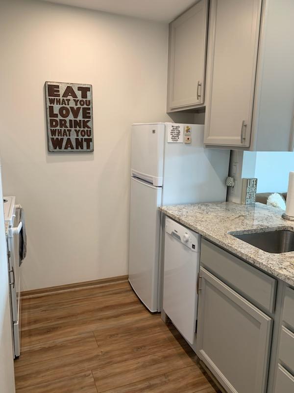 kitchen featuring dishwasher, stove, sink, dark hardwood / wood-style floors, and light stone counters