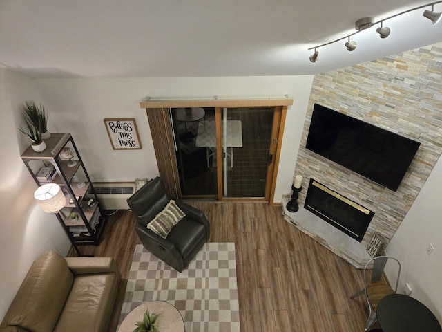 living room with a fireplace, rail lighting, wood-type flooring, and radiator heating unit