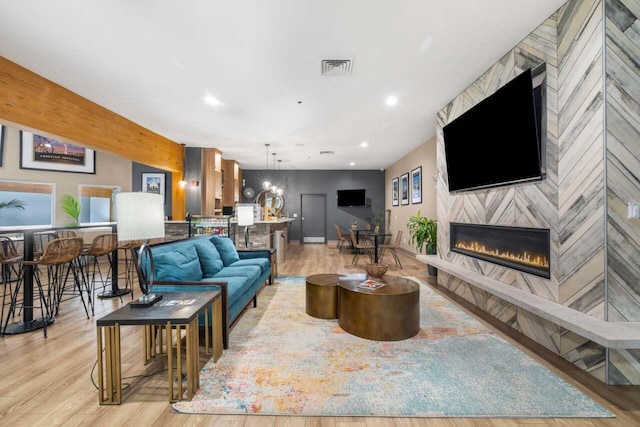 living room with beam ceiling, a fireplace, and light hardwood / wood-style floors