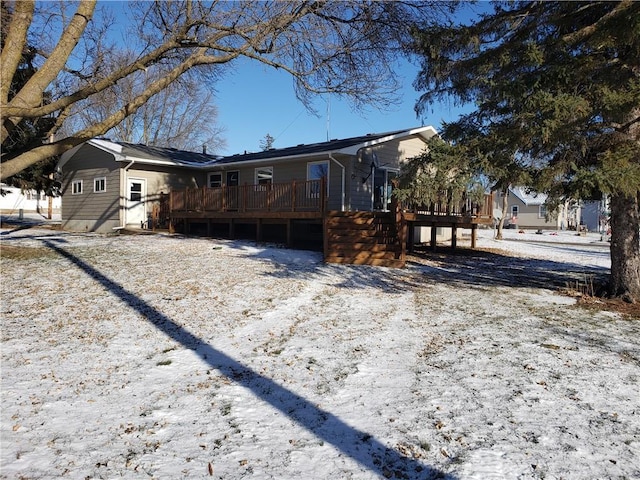 snow covered back of property with a deck