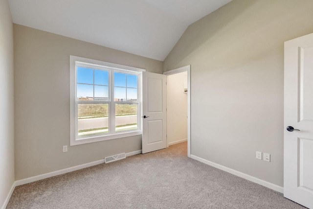 carpeted empty room with lofted ceiling