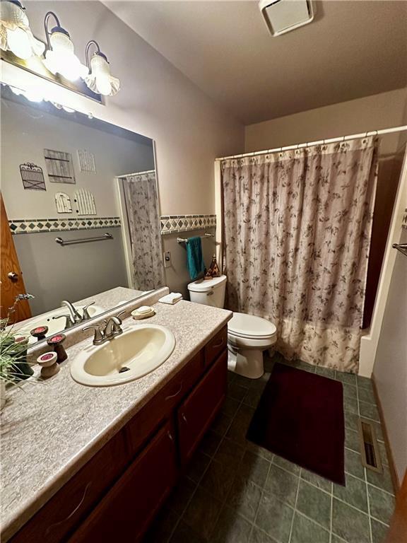 full bathroom featuring vanity, shower / tub combo, and toilet