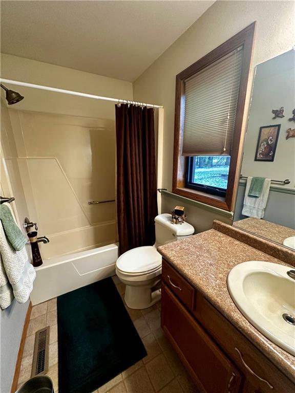 full bathroom with toilet, tile patterned floors, vanity, and shower / tub combo with curtain